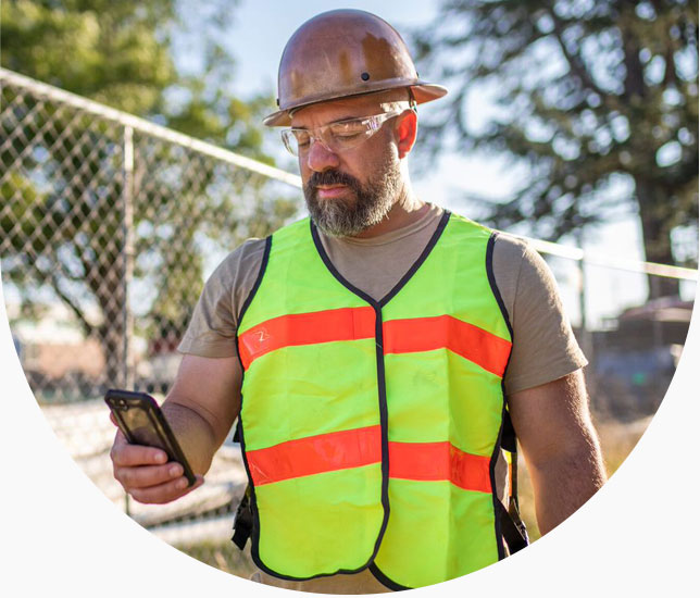 Construction worker looks at phone