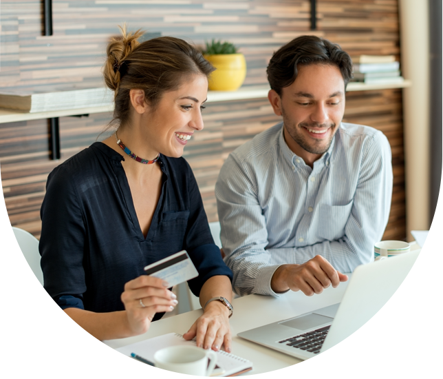Two employees work together on laptop with credit card